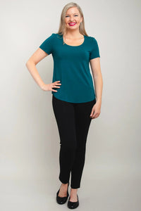 Woman wearing a teal top and black pants against a plain background