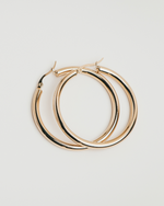 Load image into Gallery viewer, Gold hoop earrings on a light gray background
