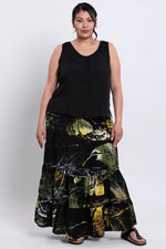 Load image into Gallery viewer, Woman wearing a black sleeveless tank and a long, batik skirt on a white background
