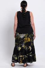 Load image into Gallery viewer, Woman wearing a black sleeveless tank and a long, batik skirt on a white background
