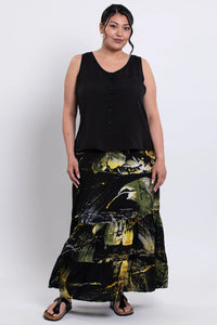 Woman wearing a black sleeveless tank and a long, batik skirt on a white background