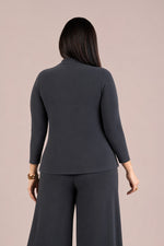 Load image into Gallery viewer, A woman shown from the back wearing a dark charcoal gray long-sleeve top and matching wide-leg pants against a solid pale pink background.
