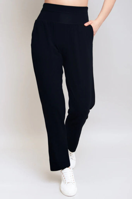 Person wearing black pants and white sneakers on a plain background