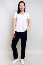 Load image into Gallery viewer, Woman wearing a white t-shirt and black pants against a plain background

