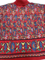 Load image into Gallery viewer, A close-up of a red knit sweater featuring an intricate multicolor floral and geometric pattern across the body and a wide decorative border near the hem.
