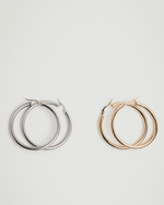 Load image into Gallery viewer, Pair of hoop earrings, one silver and one gold, on a white background
